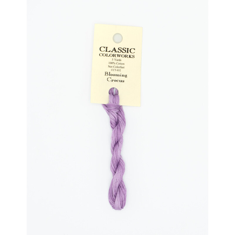 A skein of purple embroidery floss, twisted and bundled, with a cream and black label featuring the brand name and color information.