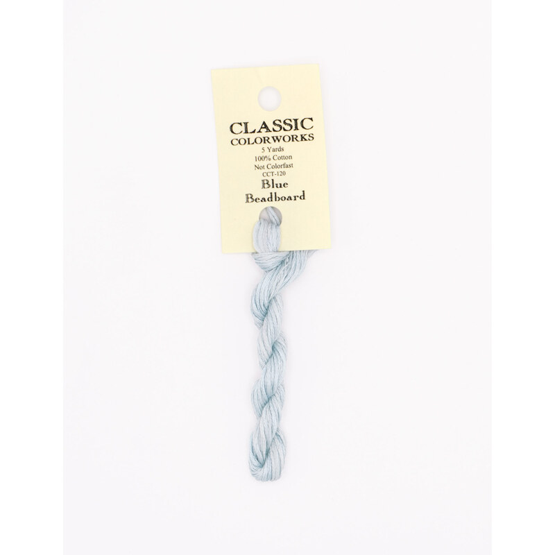 A skein of icy blue embroidery floss, twisted and bundled, with a cream and black label featuring the brand name and color information.
