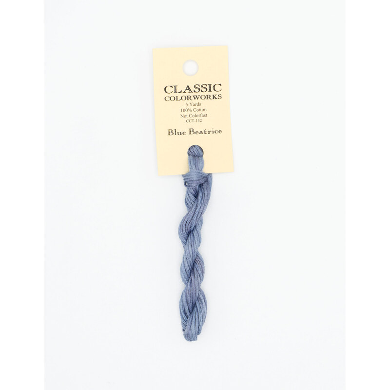 A skein of gray blue embroidery floss, twisted and bundled, with a cream and black label featuring the brand name and color information.