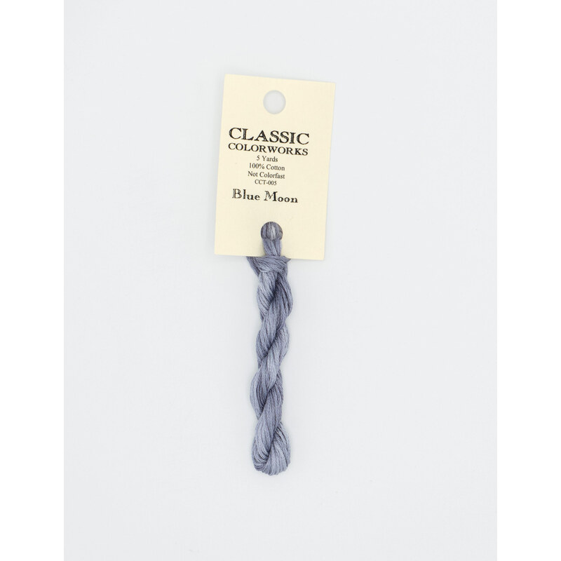 A skein of gray blue embroidery floss, twisted and bundled, with a cream and black label featuring the brand name and color information.