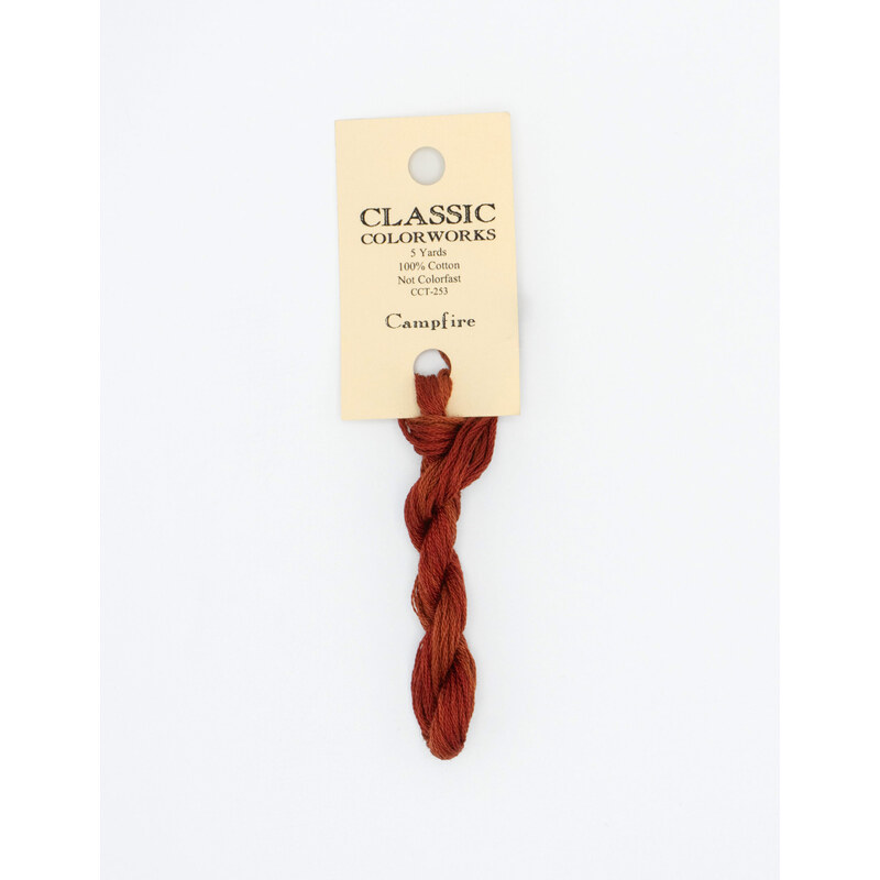 A skein of brick red embroidery floss, twisted and bundled, with a cream and black label featuring the brand name and color information.
