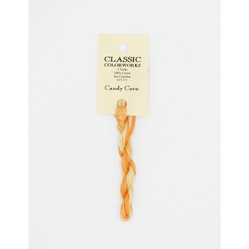 A skein of variegated orange and yellow embroidery floss, twisted and bundled, with a cream and black label featuring the brand name and color information.