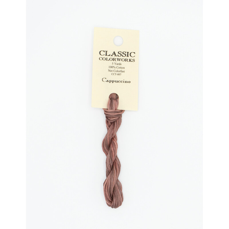 A skein of variegated muted pink and warm gray embroidery floss, twisted and bundled, with a cream and black label featuring the brand name and color information.