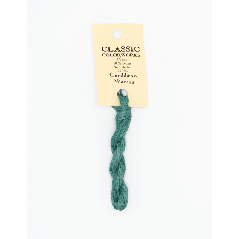 A skein of ocean blue embroidery floss, twisted and bundled, with a cream and black label featuring the brand name and color information.