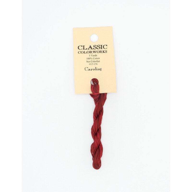 A skein of deep red embroidery floss, twisted and bundled, with a cream and black label featuring the brand name and color information.