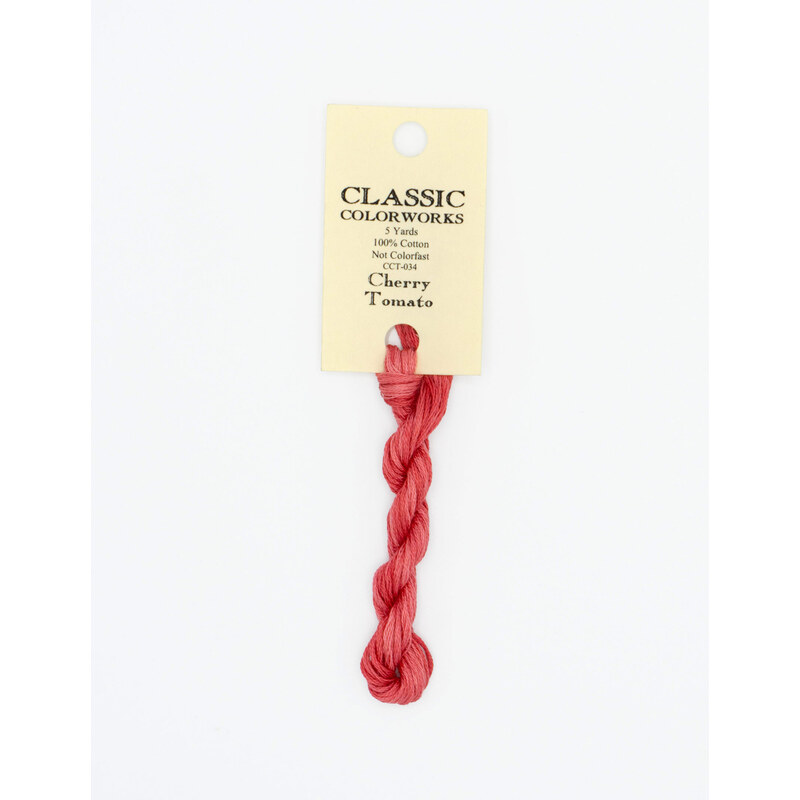 A skein of rose red embroidery floss, twisted and bundled, with a cream and black label featuring the brand name and color information.