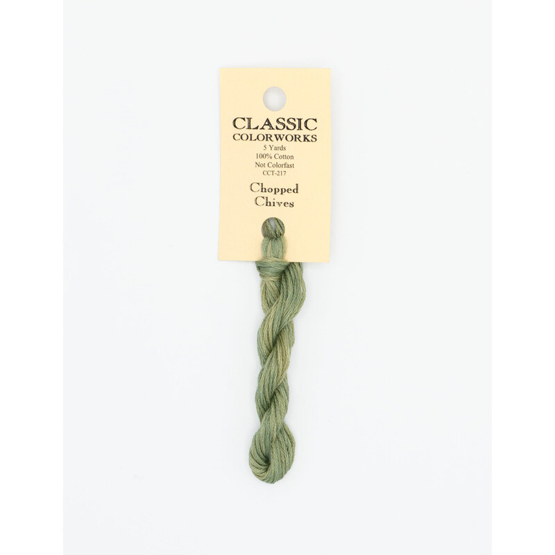A skein of light green embroidery floss, twisted and bundled, with a cream and black label featuring the brand name and color information.