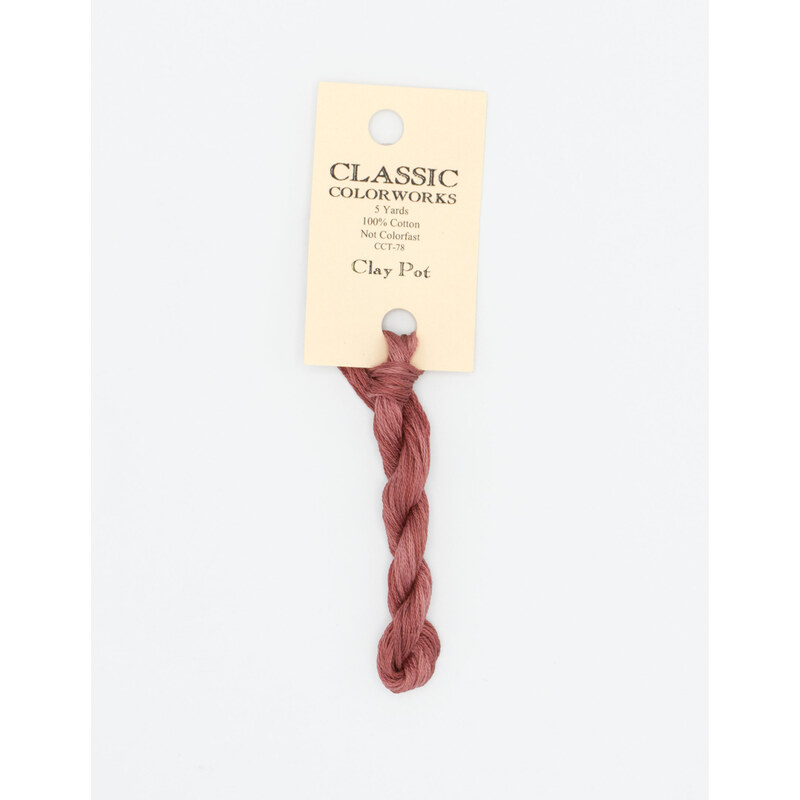 A skein of light terra cotta embroidery floss, twisted and bundled, with a cream and black label featuring the brand name and color information.