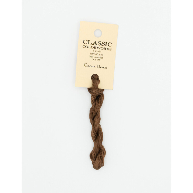 A skein of brown embroidery floss, twisted and bundled, with a cream and black label featuring the brand name and color information.