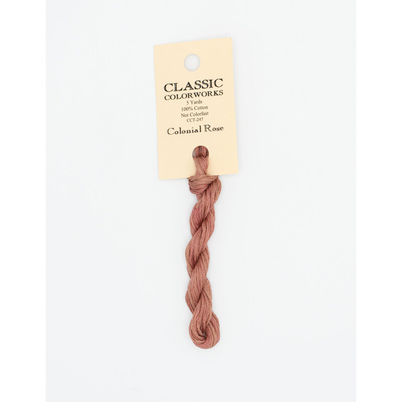 A skein of dusty rose embroidery floss, twisted and bundled, with a cream and black label featuring the brand name and color information.