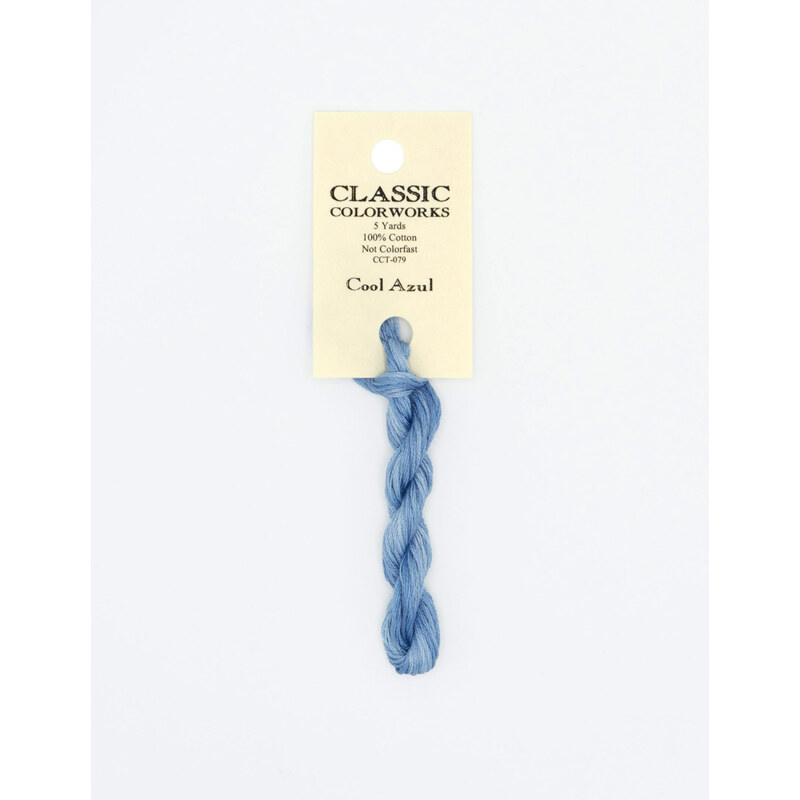 A skein of ocean blue embroidery floss, twisted and bundled, with a cream and black label featuring the brand name and color information.