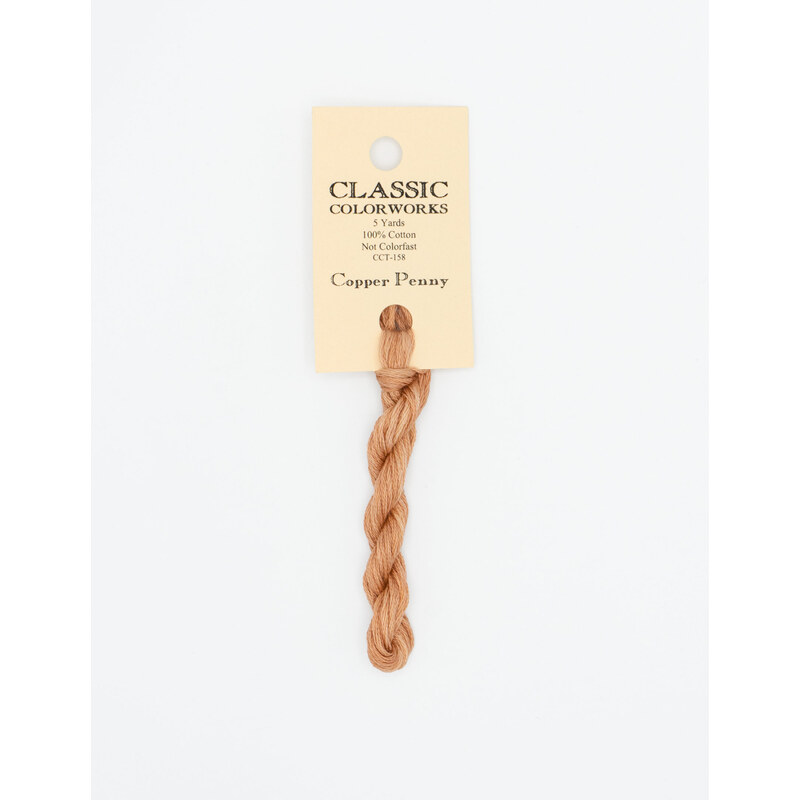A skein of light copper embroidery floss, twisted and bundled, with a cream and black label featuring the brand name and color information.