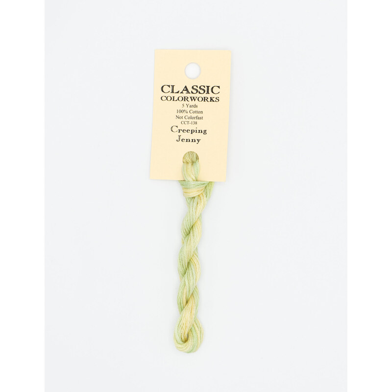 A skein of variegated light yellow and light green embroidery floss, twisted and bundled, with a cream and black label featuring the brand name and color information.