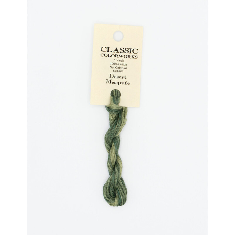 A skein of sage green embroidery floss, twisted and bundled, with a cream and black label featuring the brand name and color information.