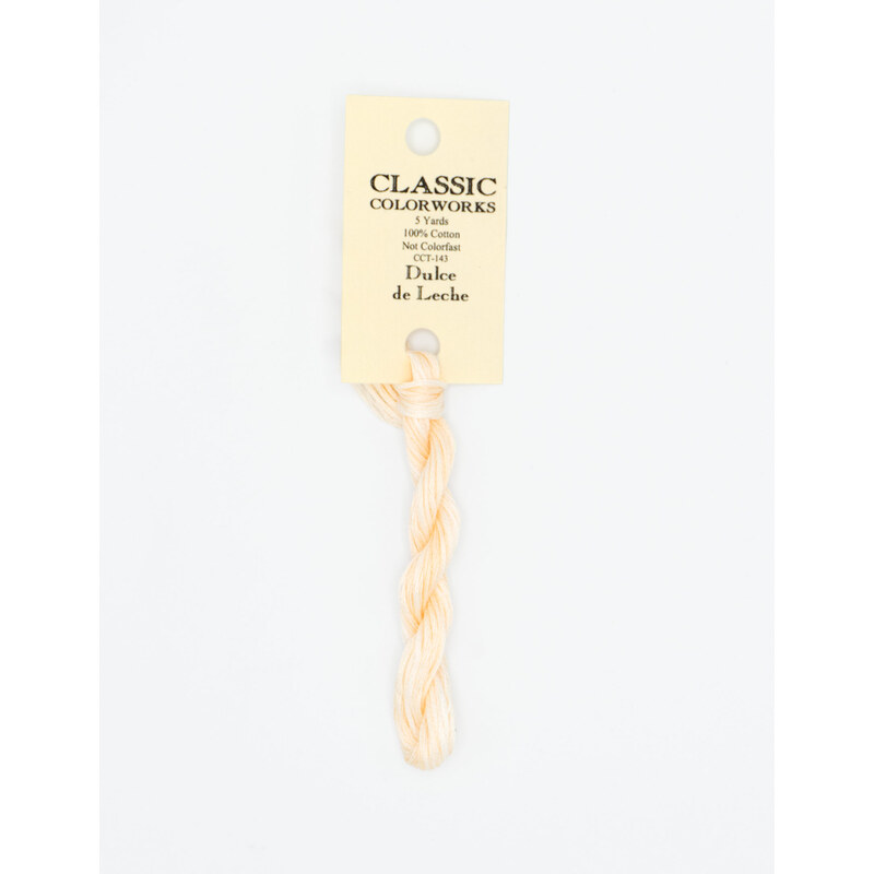 A skein of very light peach embroidery floss, twisted and bundled, with a cream and black label featuring the brand name and color information.