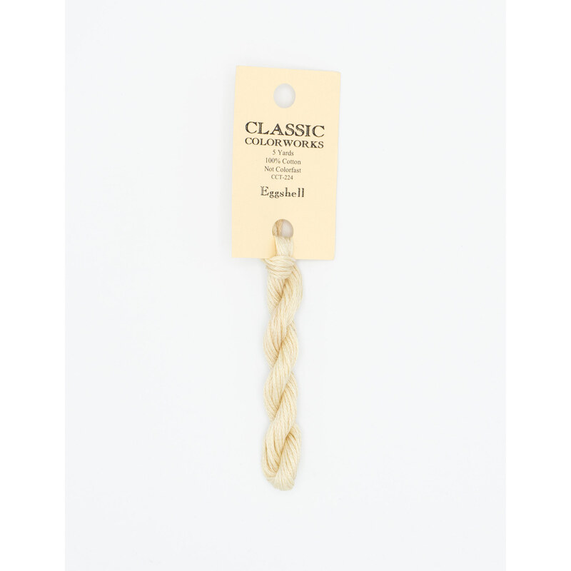 A skein of off-white embroidery floss, twisted and bundled, with a cream and black label featuring the brand name and color information.