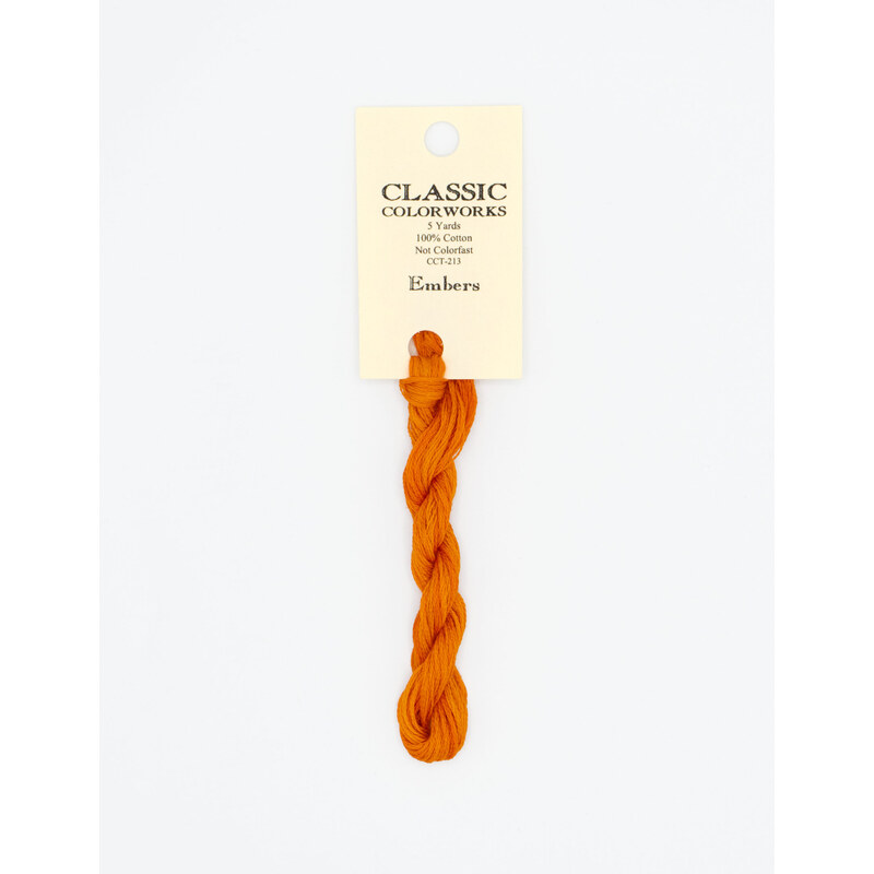 A skein of bright orange embroidery floss, twisted and bundled, with a cream and black label featuring the brand name and color information.