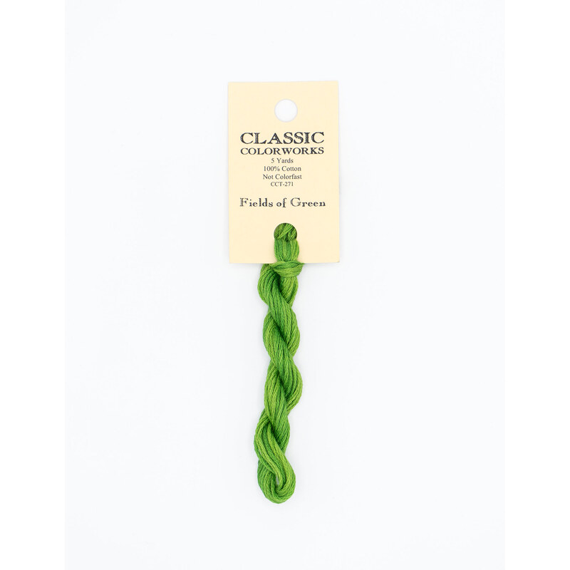 A skein of bright green embroidery floss, twisted and bundled, with a cream and black label featuring the brand name and color information.