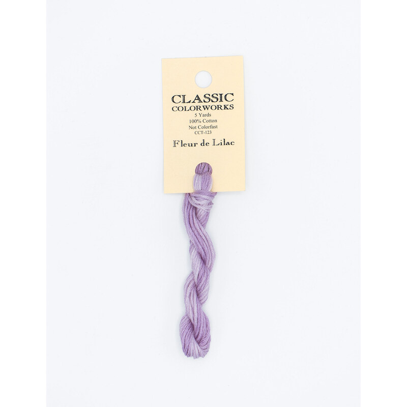 A skein of light purple embroidery floss, twisted and bundled, with a cream and black label featuring the brand name and color information.