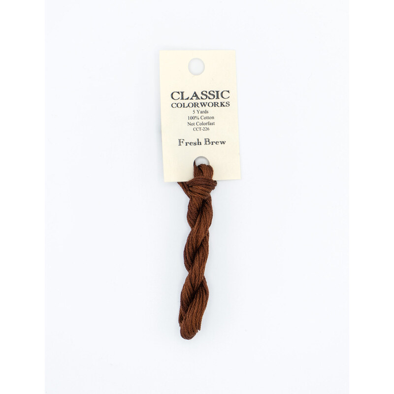 A skein of coffee brown embroidery floss, twisted and bundled, with a cream and black label featuring the brand name and color information.