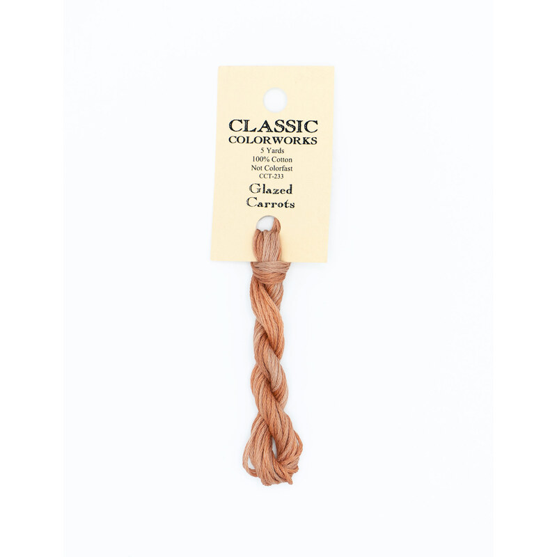 A skein of peach embroidery floss, twisted and bundled, with a cream and black label featuring the brand name and color information.