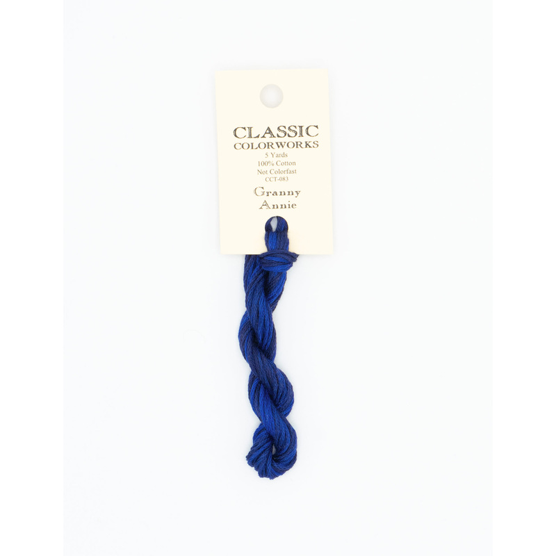 A skein of navy blue embroidery floss, twisted and bundled, with a cream and black label featuring the brand name and color information.
