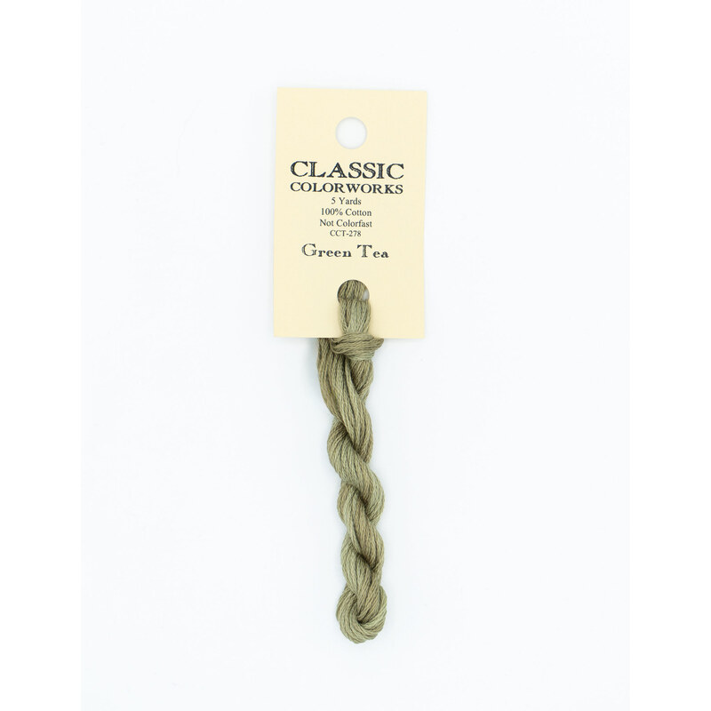 A skein of light green embroidery floss, twisted and bundled, with a cream and black label featuring the brand name and color information.