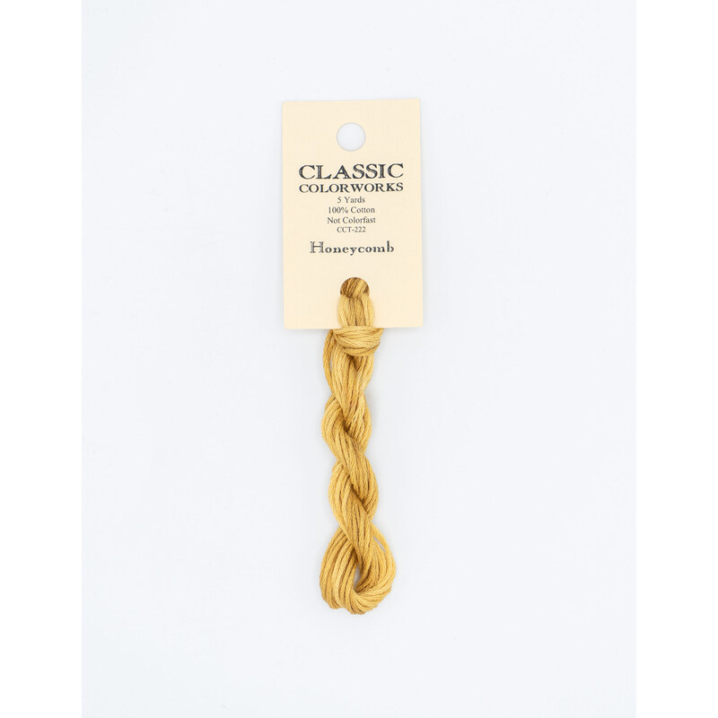 A skein of golden yellow embroidery floss, twisted and bundled, with a cream and black label featuring the brand name and color information.