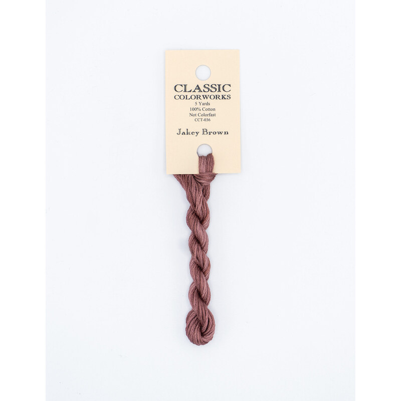 A skein of mauve brown embroidery floss, twisted and bundled, with a cream and black label featuring the brand name and color information.