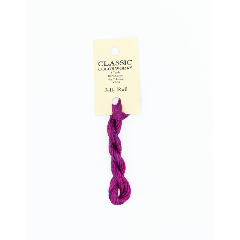 A skein of magenta purple embroidery floss, twisted and bundled, with a cream and black label featuring the brand name and color information.