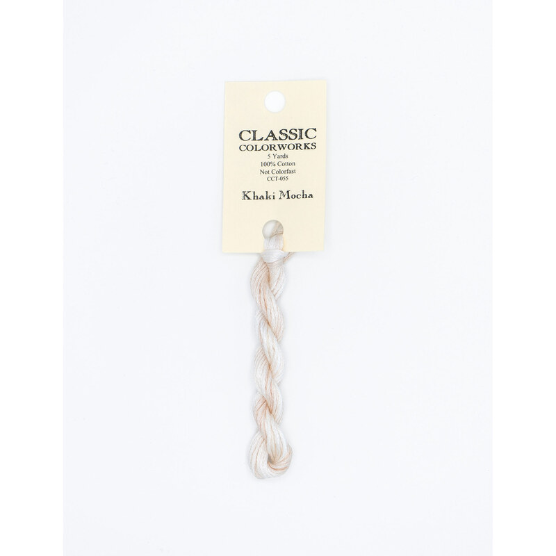 A skein of cream embroidery floss, twisted and bundled, with a cream and black label featuring the brand name and color information.