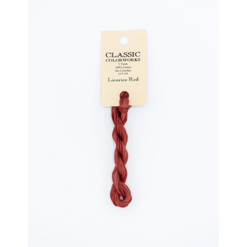 A skein of red embroidery floss, twisted and bundled, with a cream and black label featuring the brand name and color information.