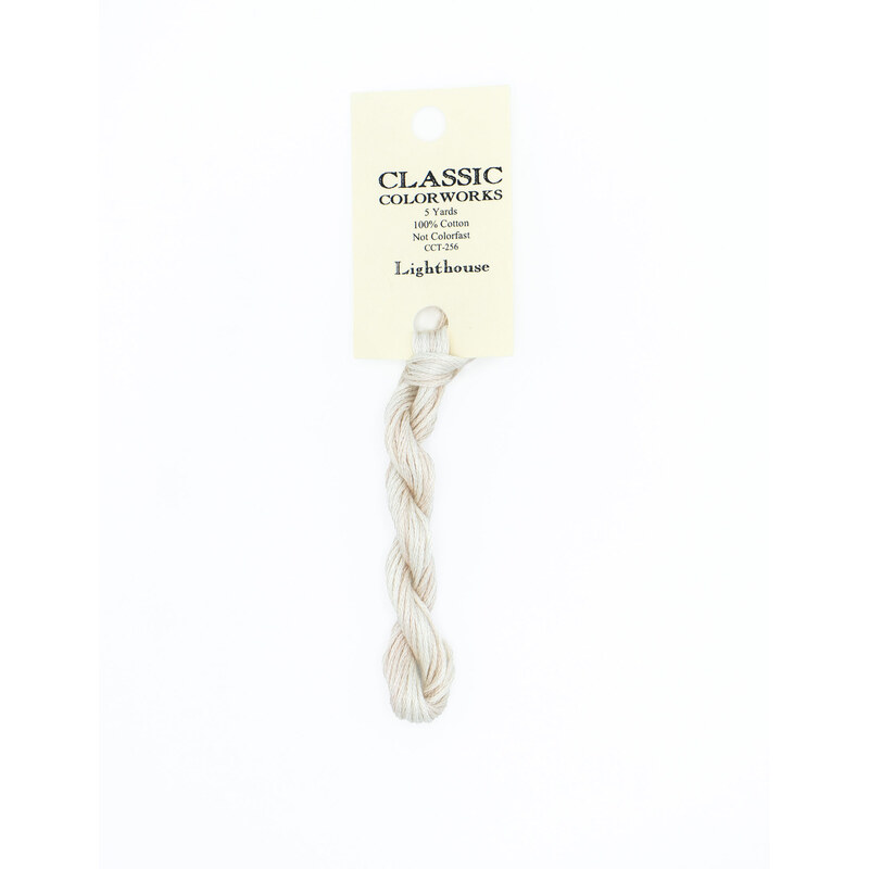 A skein of cream embroidery floss, twisted and bundled, with a cream and black label featuring the brand name and color information.