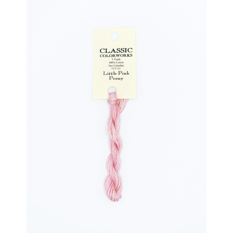 A skein of light pink embroidery floss, twisted and bundled, with a cream and black label featuring the brand name and color information.