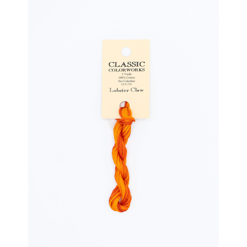 A skein of variegated orange embroidery floss, twisted and bundled, with a cream and black label featuring the brand name and color information.