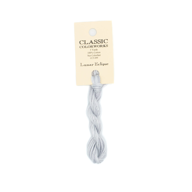 A skein of cloud gray embroidery floss, twisted and bundled, with a cream and black label featuring the brand name and color information.