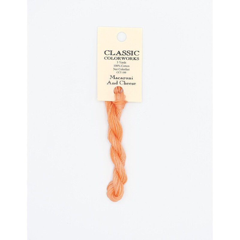 A skein of peach embroidery floss, twisted and bundled, with a cream and black label featuring the brand name and color information.