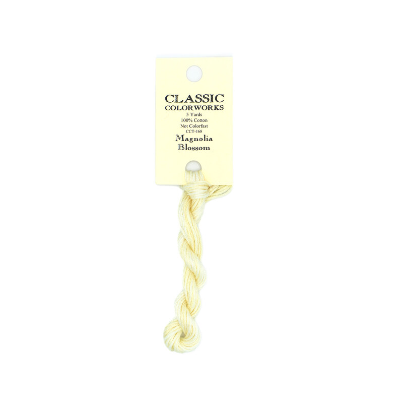 A skein of cream embroidery floss, twisted and bundled, with a cream and black label featuring the brand name and color information.