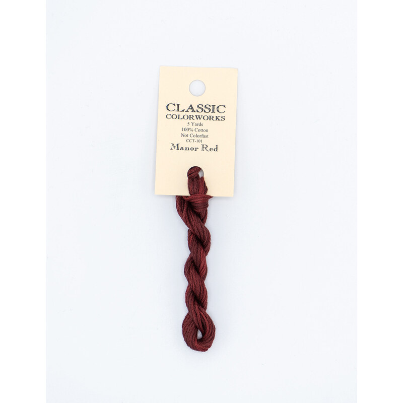 A skein of red embroidery floss, twisted and bundled, with a cream and black label featuring the brand name and color information.