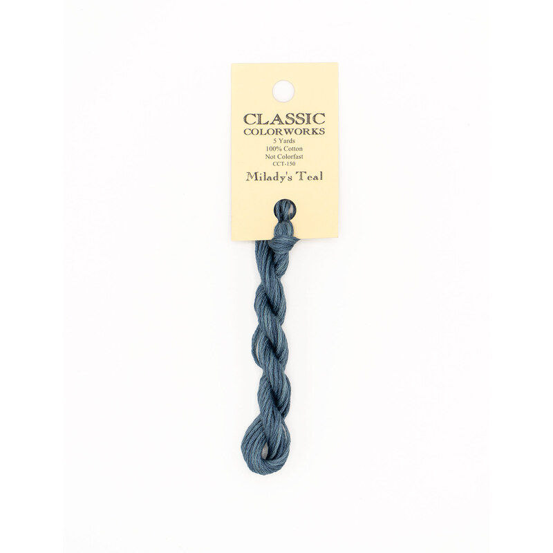 A skein of steel blue embroidery floss, twisted and bundled, with a cream and black label featuring the brand name and color information.