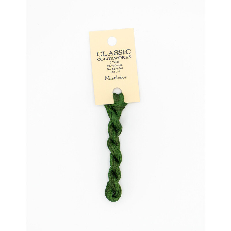 A skein of dark green embroidery floss, twisted and bundled, with a cream and black label featuring the brand name and color information.