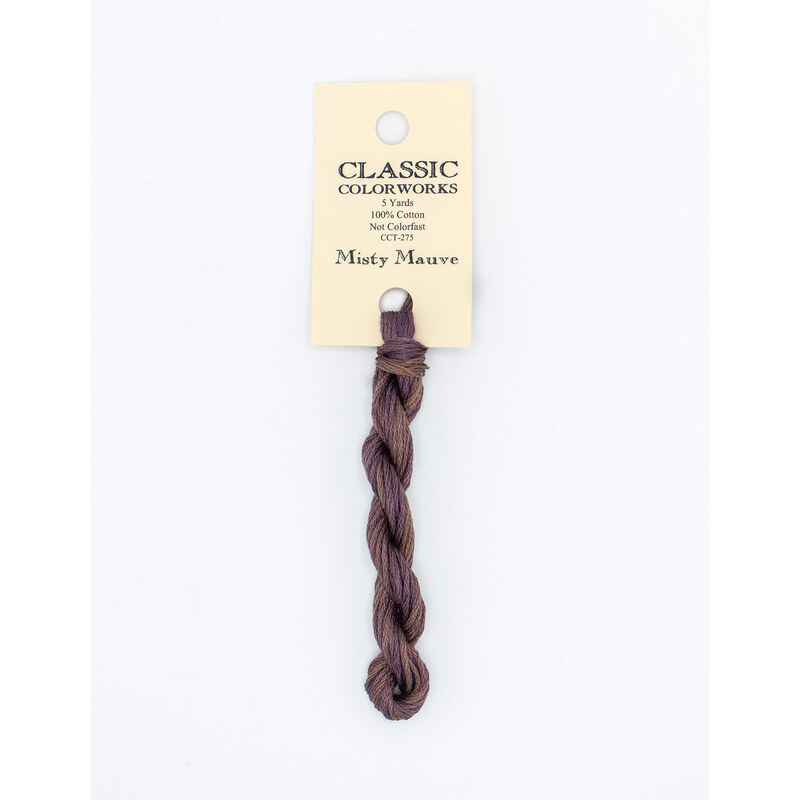 A skein of muted purple embroidery floss, twisted and bundled, with a cream and black label featuring the brand name and color information.