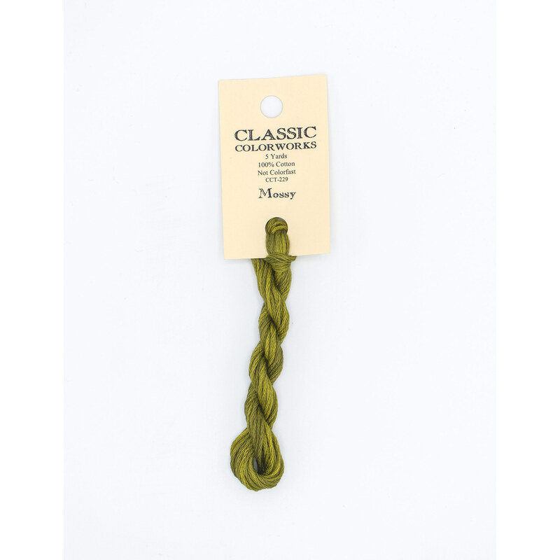 A skein of green embroidery floss, twisted and bundled, with a cream and black label featuring the brand name and color information.