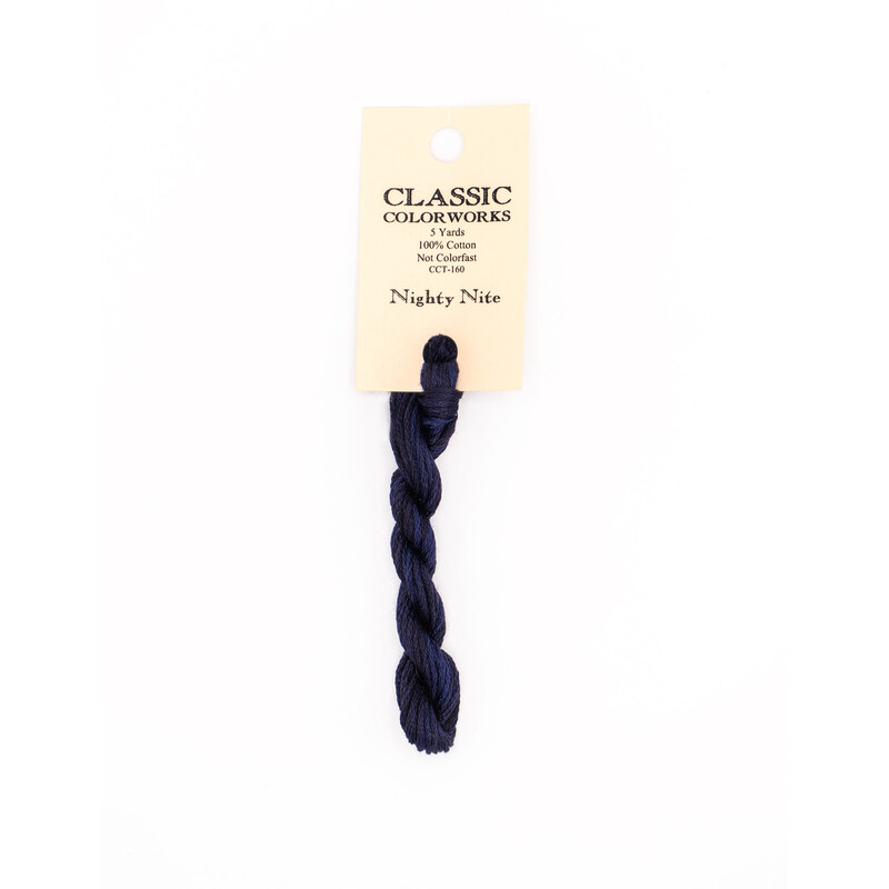 A skein of dark blue embroidery floss, twisted and bundled, with a cream and black label featuring the brand name and color information.