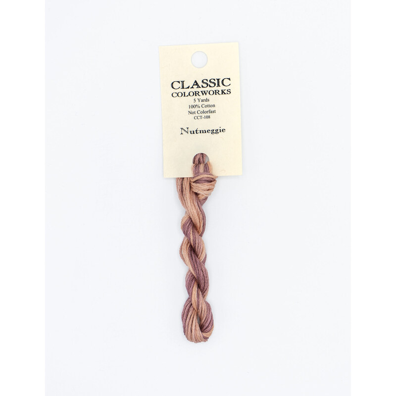 A skein of variegated pink and purple embroidery floss, twisted and bundled, with a cream and black label featuring the brand name and color information.