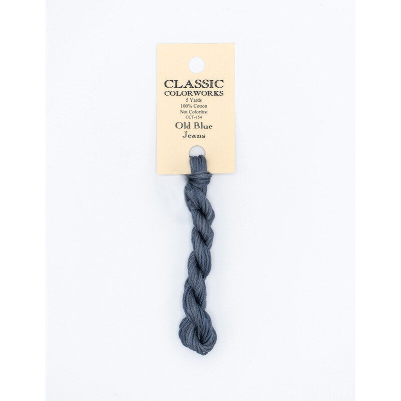 A skein of denim blue embroidery floss, twisted and bundled, with a cream and black label featuring the brand name and color information.
