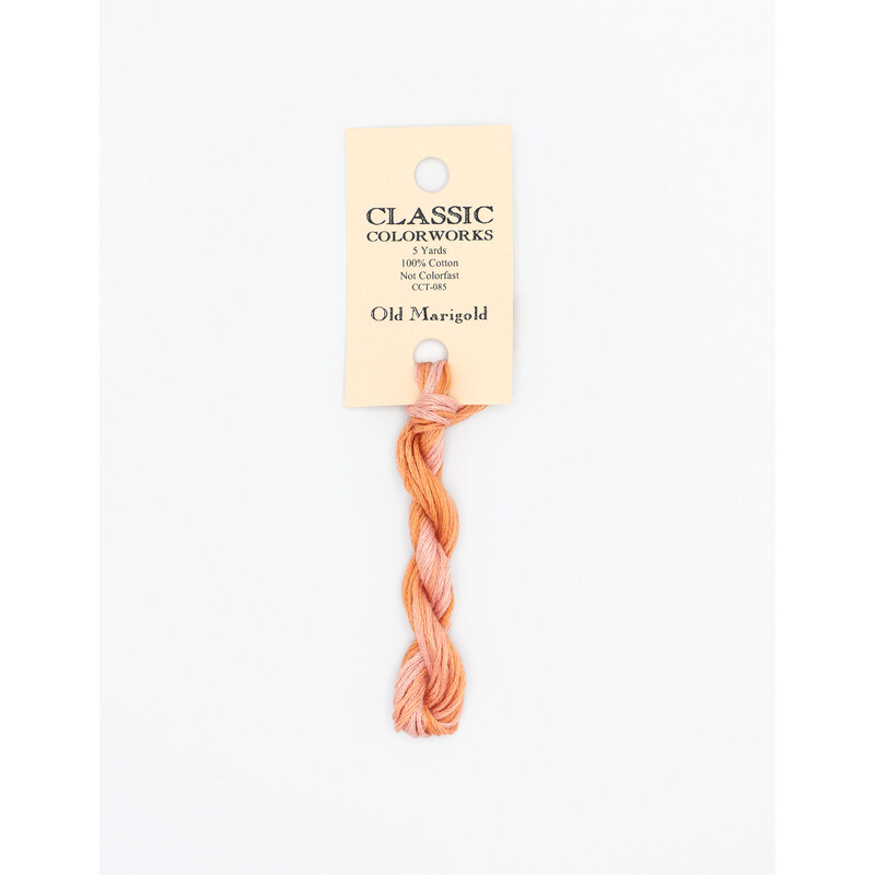 A skein of variegated peach, and pink embroidery floss, twisted and bundled, with a cream and black label featuring the brand name and color information.