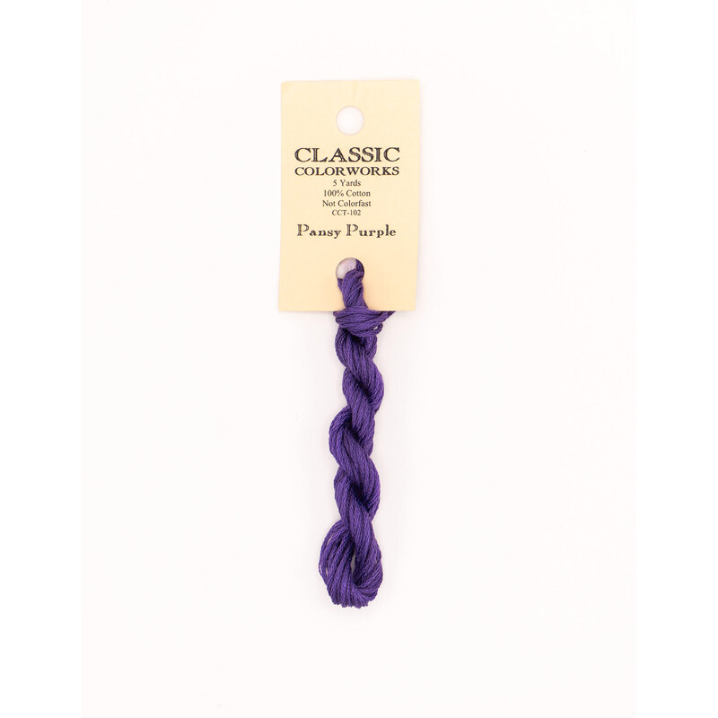 A skein of purple embroidery floss, twisted and bundled, with a cream and black label featuring the brand name and color information.