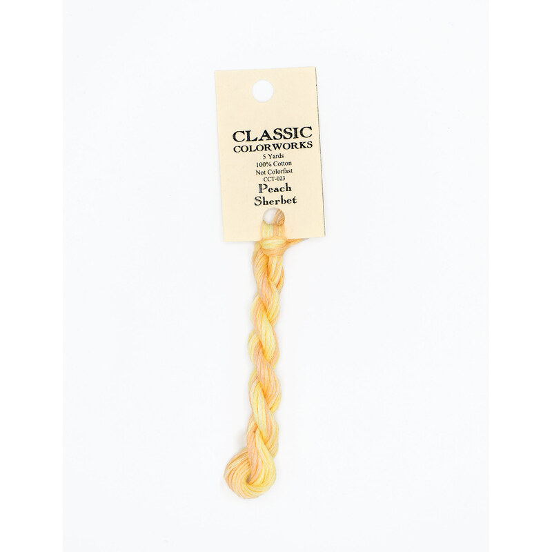 A skein of variegated peach and yellow embroidery floss, twisted and bundled, with a cream and black label featuring the brand name and color information.