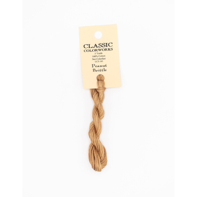 A skein of light brown embroidery floss, twisted and bundled, with a cream and black label featuring the brand name and color information.